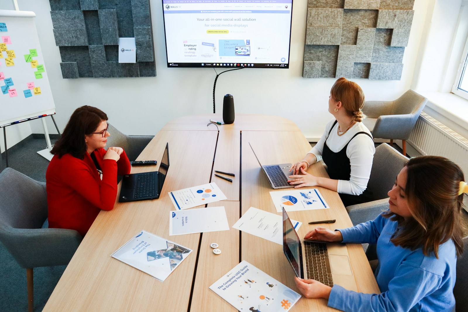 a group of people sitting around a table with laptops